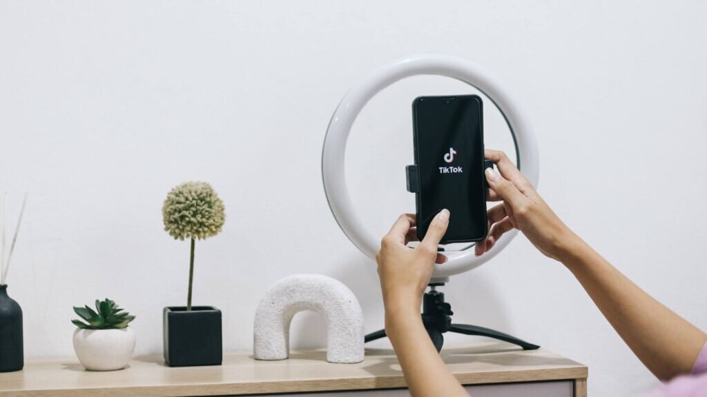 A TikTok creator holds a phone, ready to film an engaging video for their followers.