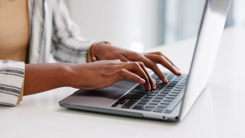 A woman typing on a laptop keyboard.