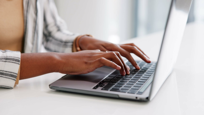 A woman typing on a laptop keyboard.