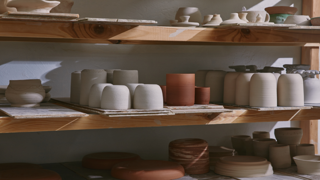 A shelf displaying various decorative pots and vases in various shapes and colors.