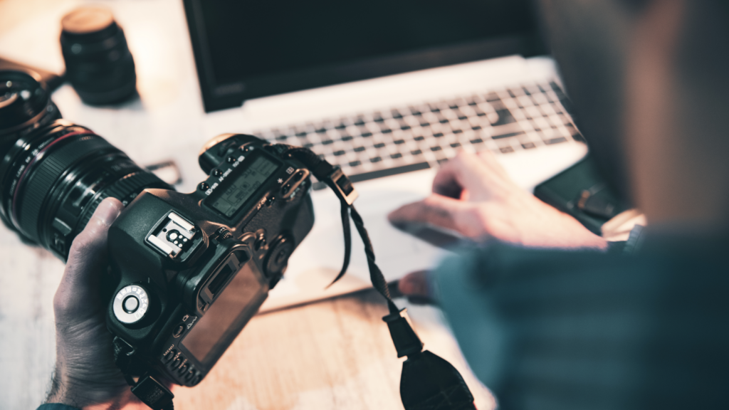 A person holding a camera in one hand and a laptop in the other.