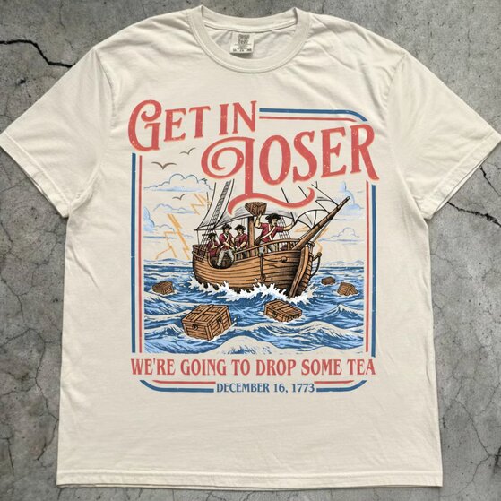 A woman posing in a beige 4th of July t-shirt that says 