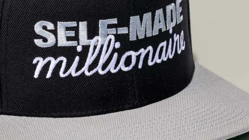 A black cap with the text "SELF-MADE millionaire" embroidered on it in white and gray.