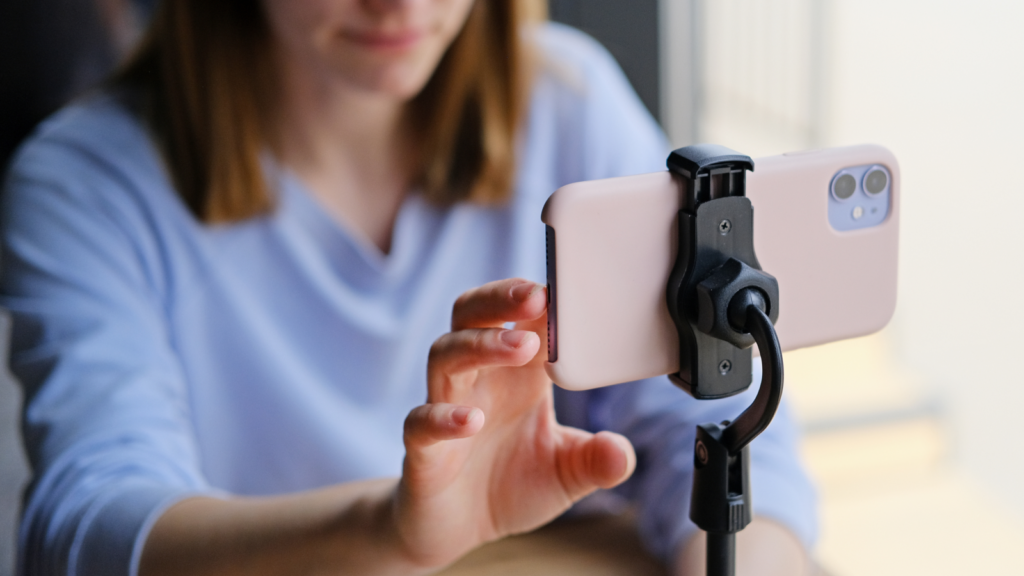A woman setting up a mobile phone camera to take a picture of a product.