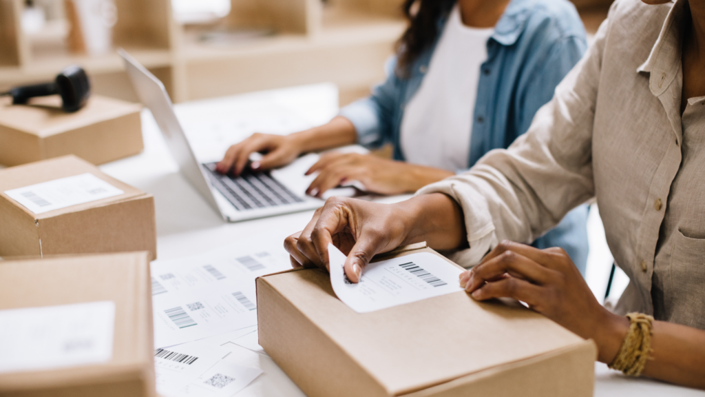 A person sticking a shipping label on a box.