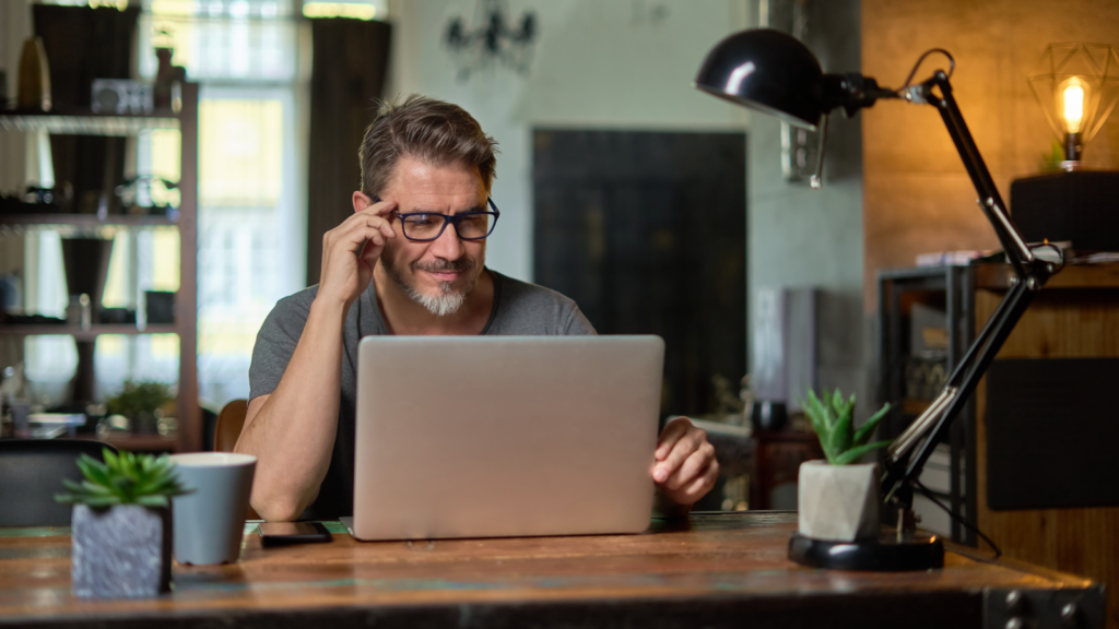A man reading from a laptop screen.