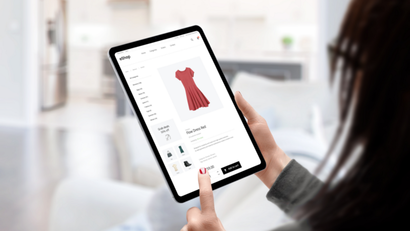 A woman choosing and ordering a dress in an online shop using a tablet.