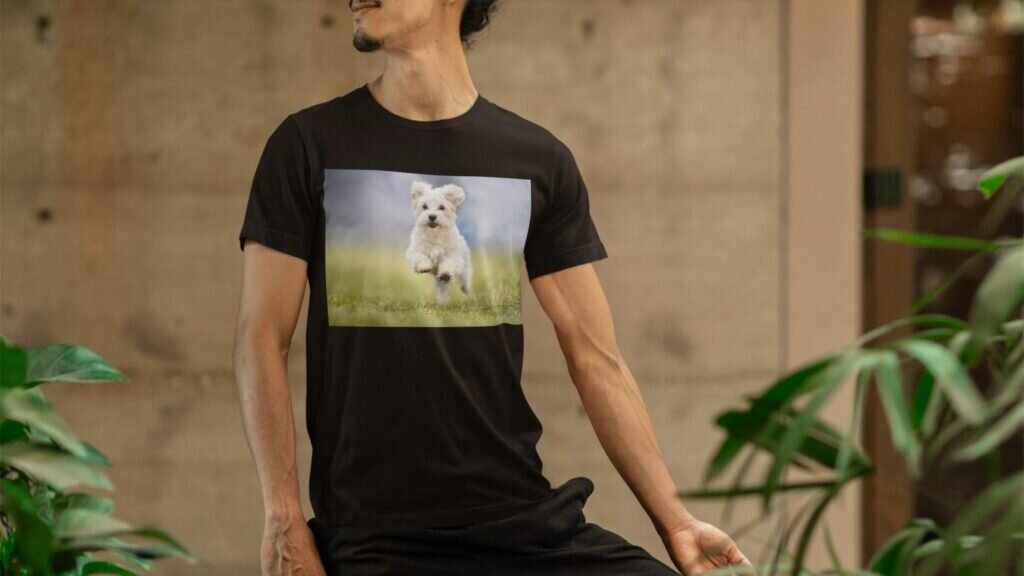 A man wearing a black t-shirt that has a design of a photo of a white puppy.