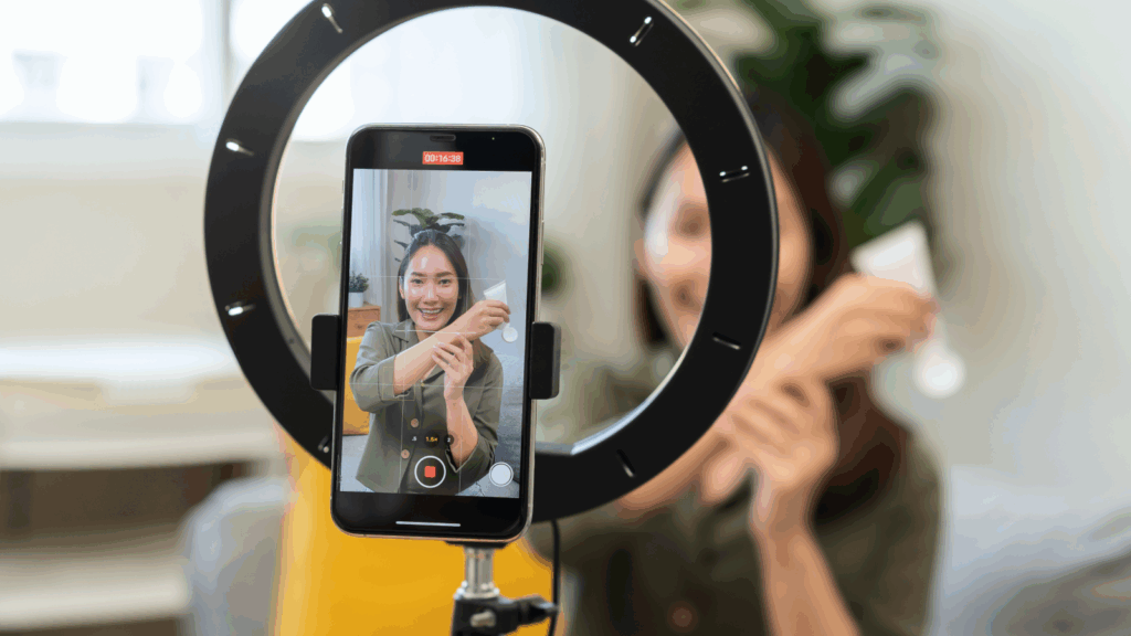 A woman is demonstrating a skincare product and recording herself using a mobile phone.