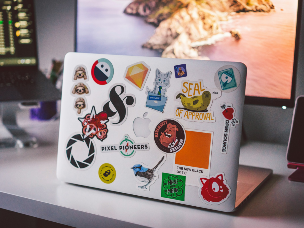 A laptop covered in colorful stickers rests on a desk, showcasing a fun and personalized workspace.