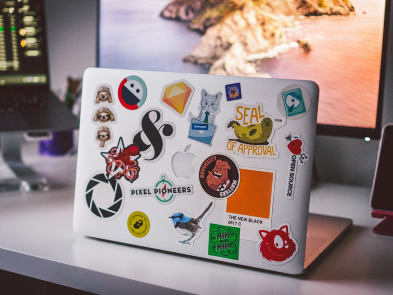 A laptop covered in colorful stickers rests on a desk, showcasing a fun and personalized workspace.