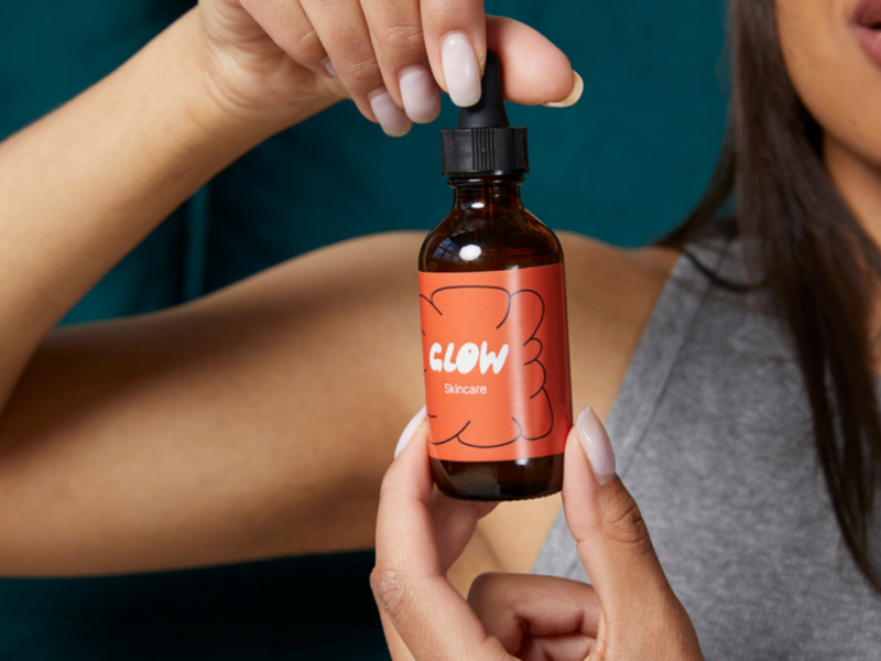 A woman holding a skincare product as an example of what to sell on Shopify.