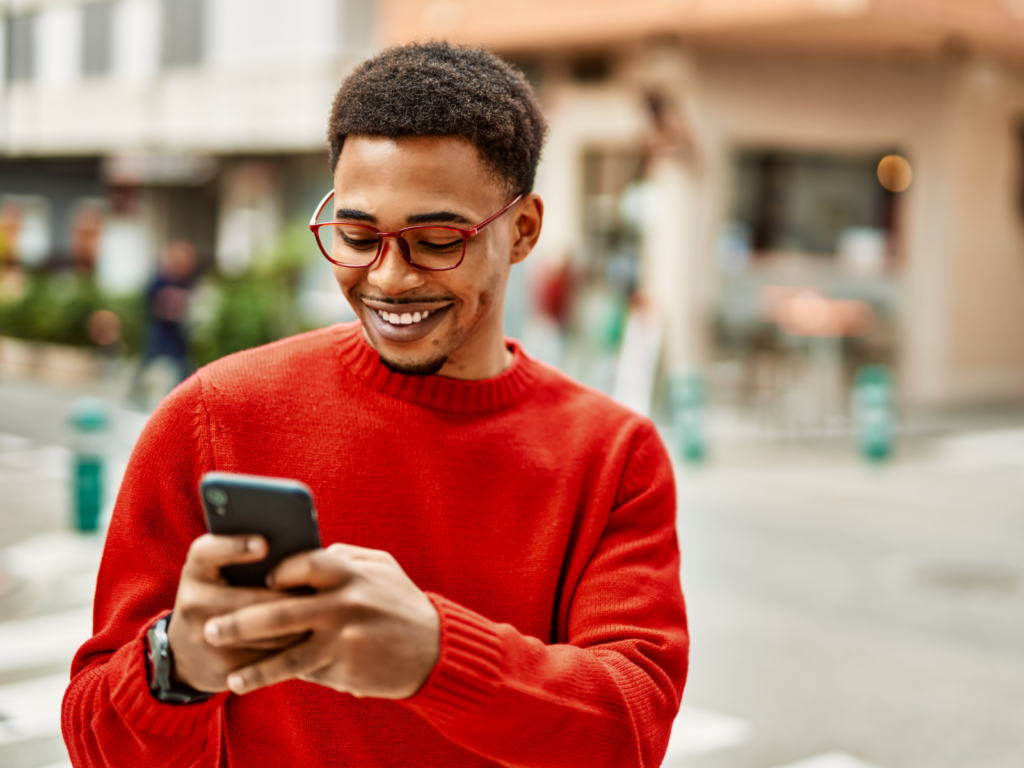A man using his phone to promote a t-shirt giveaway, showing how to make sales through social media marketing.