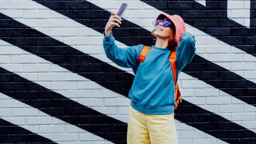 An influencer smiling and filming herself with her phone.