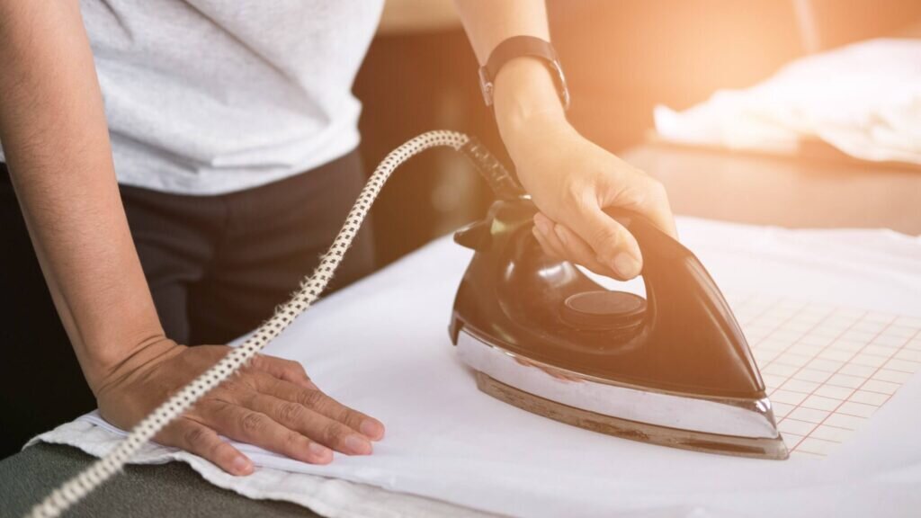 A man ironing transfer paper onto a t-shirt, getting ready to create a unique custom design