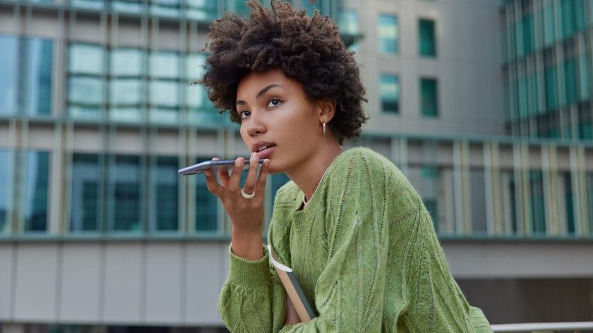 A young woman speaking into her phone.