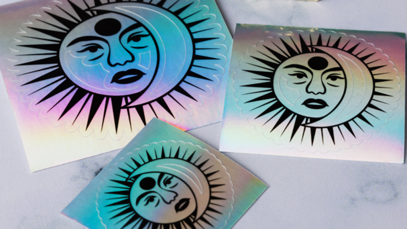 A collection of holographic stickers featuring a sun and moon design with stylized facial features.