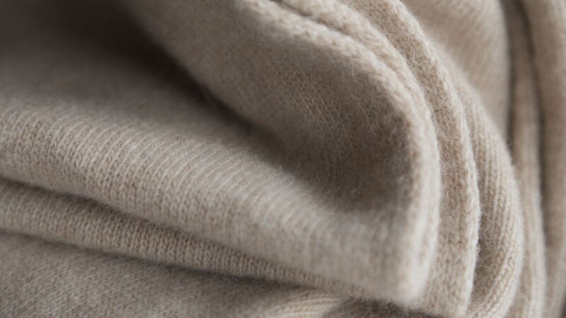 A neatly folded gray sweater rests on a wooden table, showcasing its soft texture and simple design.