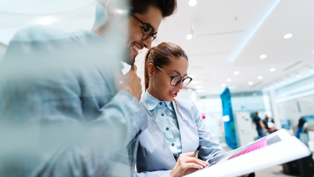 Two business professionals reviewing a document together in an office setting.