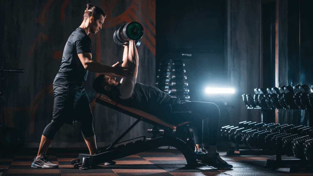 A personal trainer helps a person to exercise.