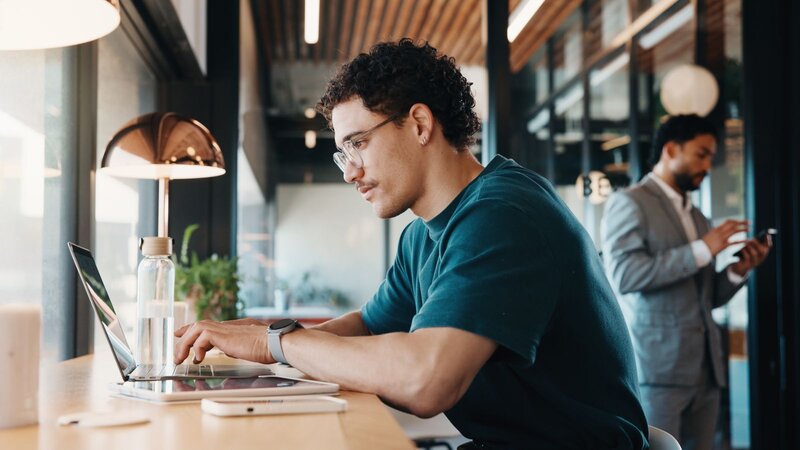 A person working on their laptop and calculating their affiliate marketing budget.