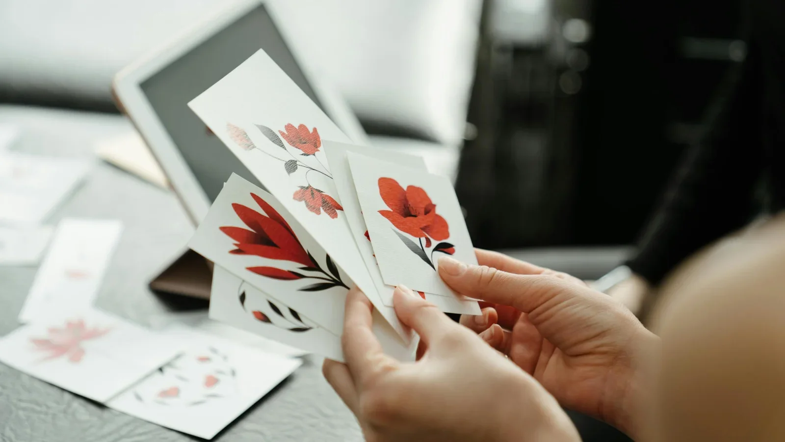 A person holding multiple stickers with different floral designs.