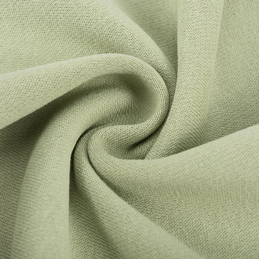 Close-up of light green cotton with a visible weave pattern, twisted into a spiral shape.