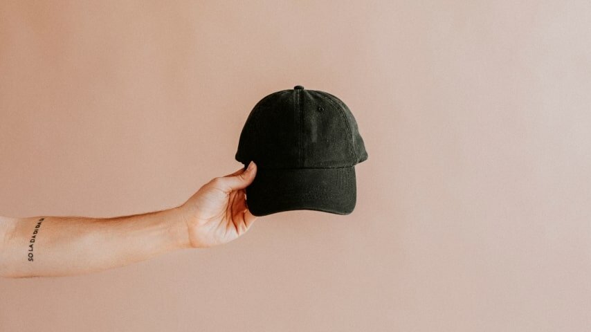 Person holding up a black baseball cap.