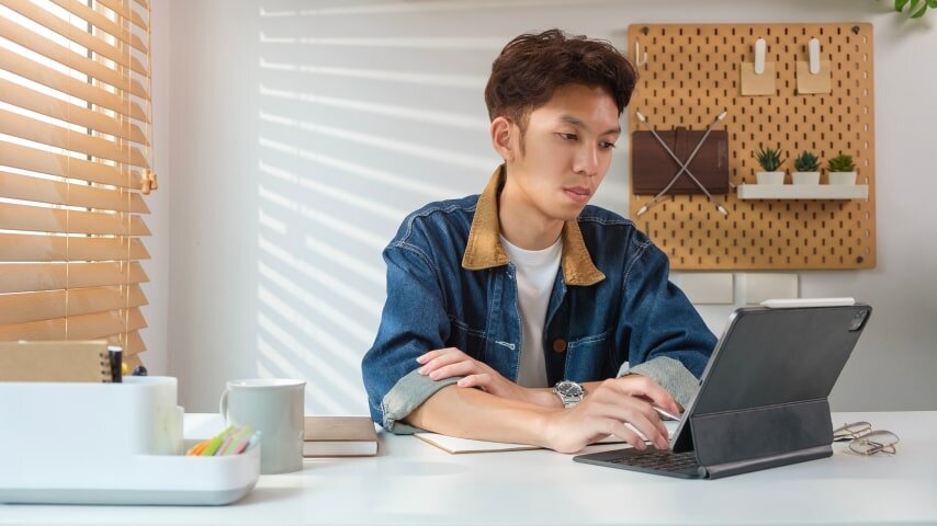A young man researching possible Etsy shop niches on his tablet.