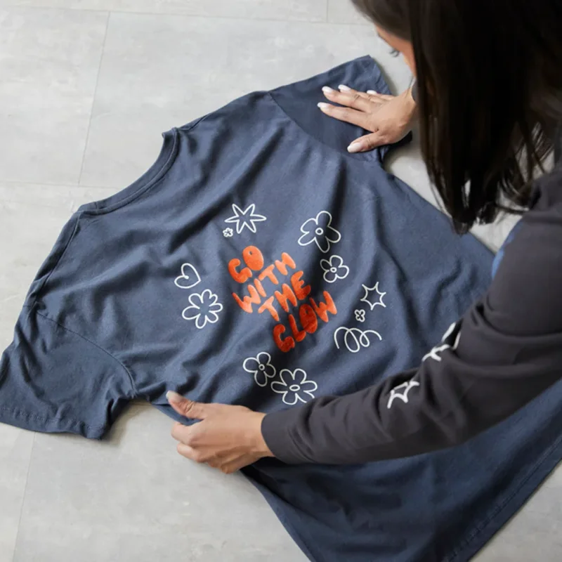 A woman looking at a custom dark-blue “Go with the glow” t-shirt.