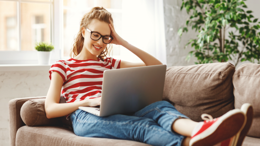 A woman sitting on a couch with a laptop on her lap.