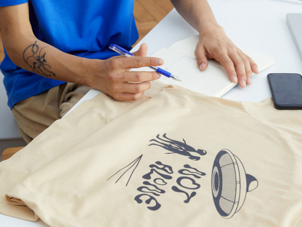 A person checking a custom t-shirt and making notes.