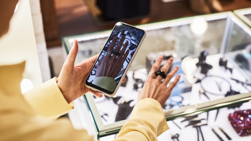 A woman is taking a picture of a ring on her hand using a smartphone.