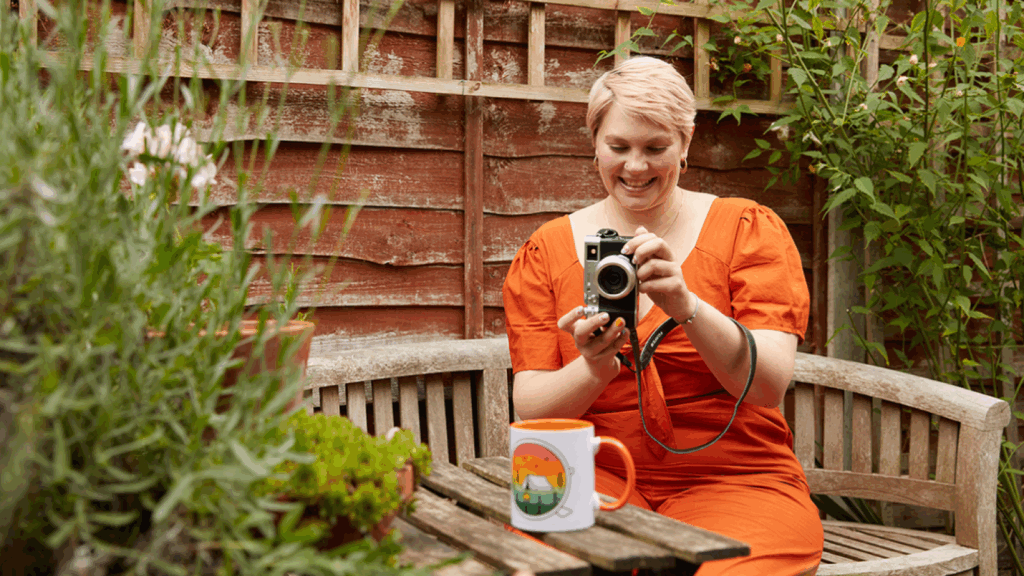 A young smiling woman taking a picture of a custom mug for her print-on-demand business.
