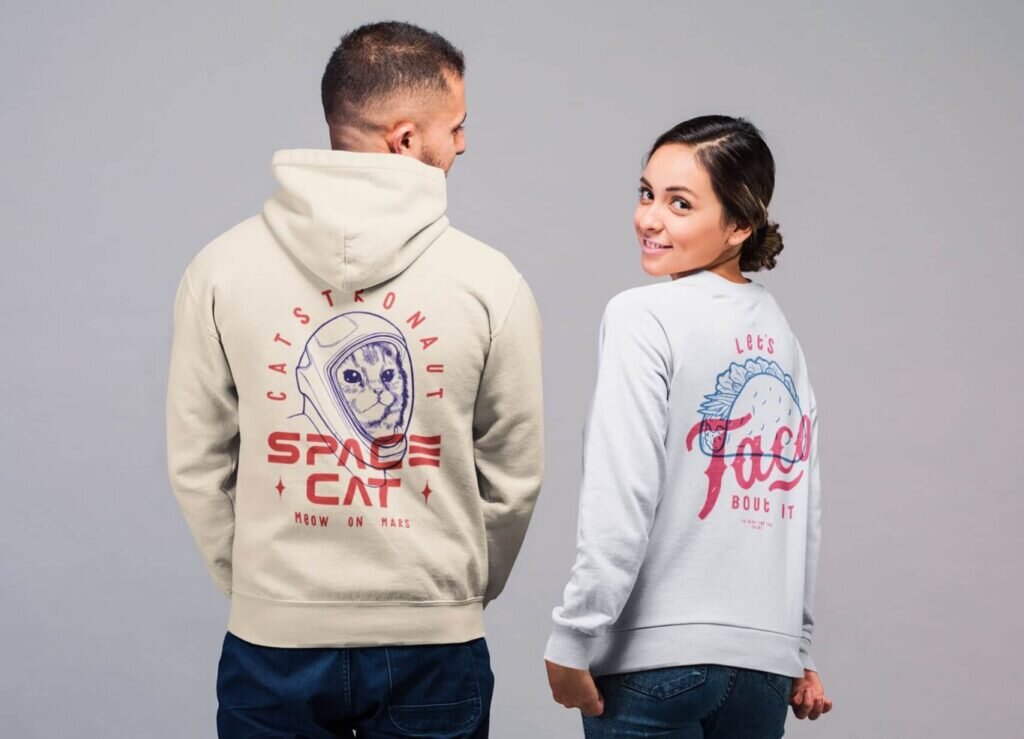 A man in a hoodie with a cat astronaut design, and a woman in a white sweatshirt with "Let's Taco" and a taco illustration.