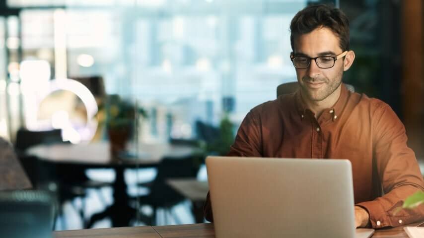 A man looking at a laptop screen and smiling.
