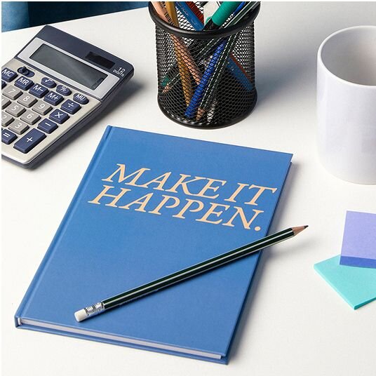 Desk with a Make it happen notebook