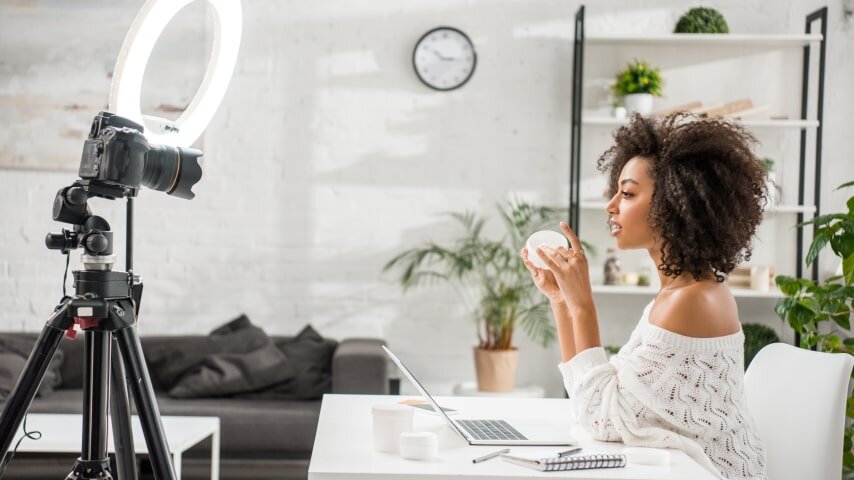 A woman filming a product review in a well-lit studio.