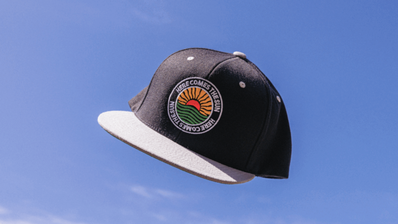 A hat featuring a sun design is floating in the air against a clear background.