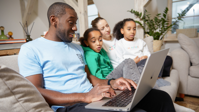 A family is seated on a couch, engaging with a laptop and managing an Etsy store together.