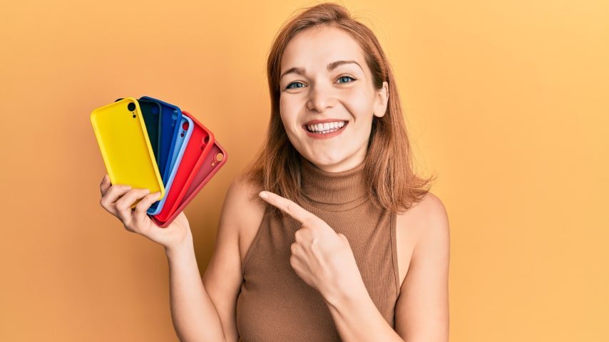 A young woman holding up a set of colorful phone cases.