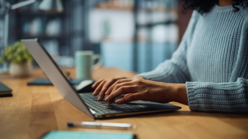 A person typing on a laptop keyboard.