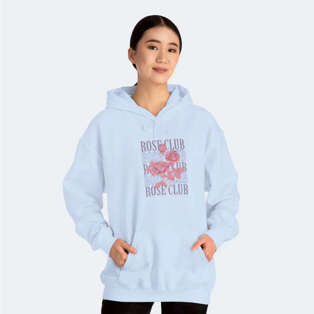 A woman in a light blue “Rose Club” hoodie against a white background.
