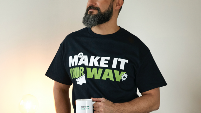 A man wearing a black “Make it your way” t-shirt and holding a mug.