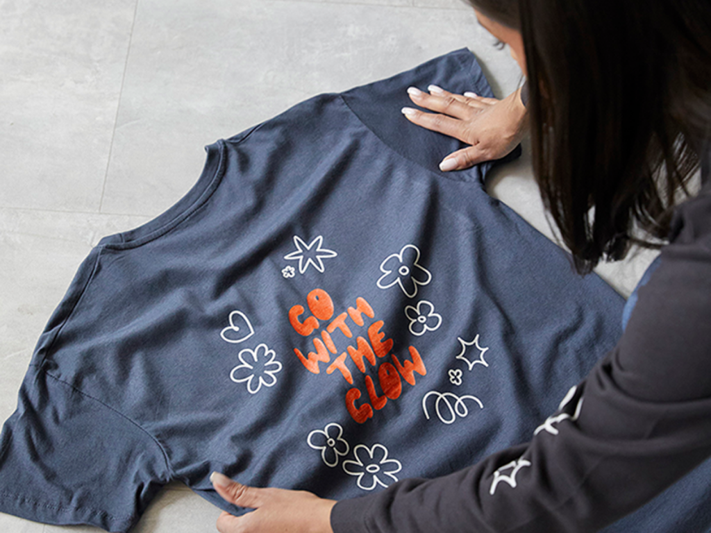 A woman checking out the quality of a custom blue “Go With the Glow” t-shirt.