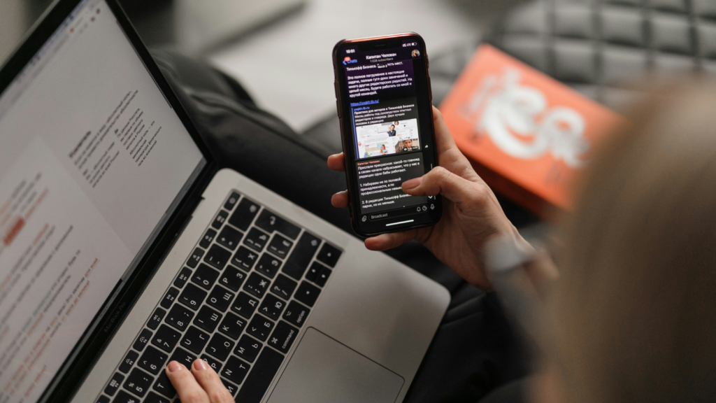 A person using a laptop and a mobile phone simultaneously.