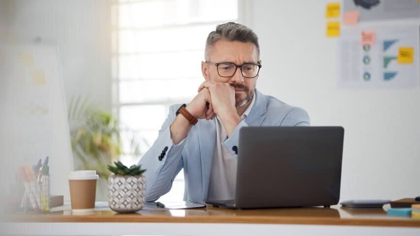 A man looking at a laptop screen and thinking.