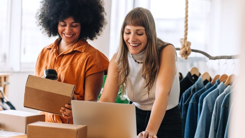 Two women packaging clothing to ship out to their Etsy customers.