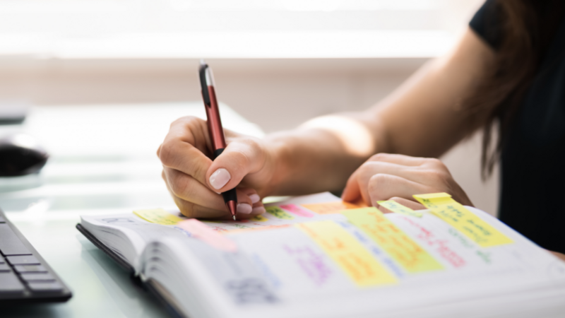 A close-up shot of a person making notes in a journal.