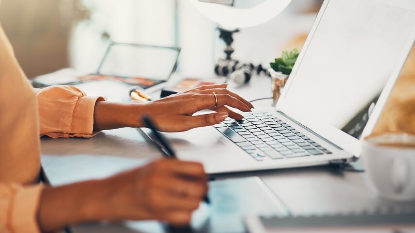 A person working on their laptop and calculating their affiliate marketing budget.